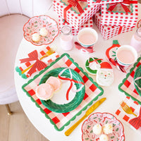 Holiday table setting with plaid cups, bow napkins, and cookie boxes