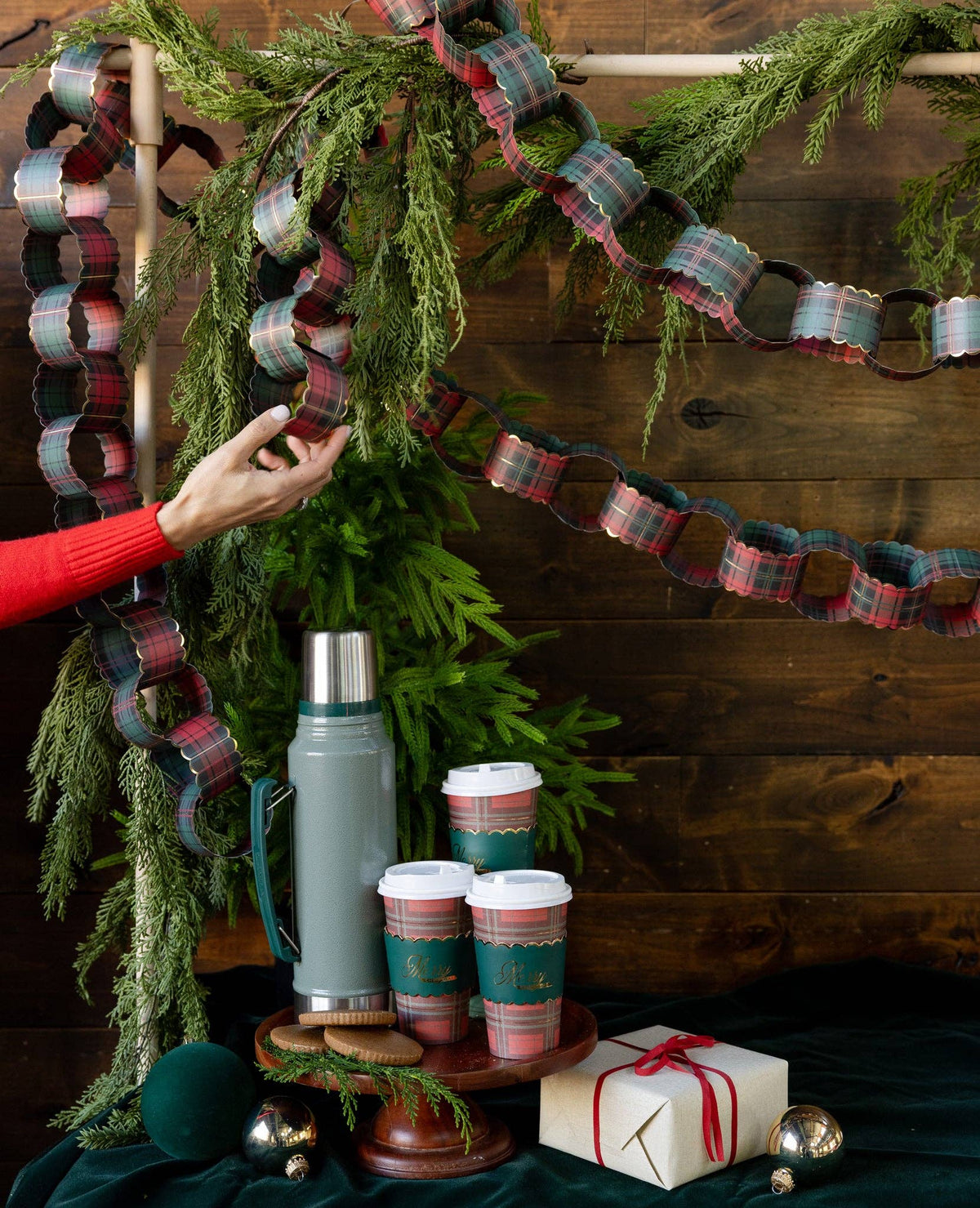 Plaid paper chain styled hanging on a wall with greenery and cups