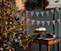 Plaid pennant banner styled with paper fans by a Christmas tree