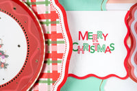 Close-up of the plaid dinner plate's scalloped edge beside a "Merry Christmas" napkin.