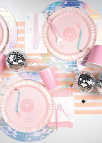 Top-down view of two place settings with iridescent disco placemats, pink cups, and guitar-themed napkins.