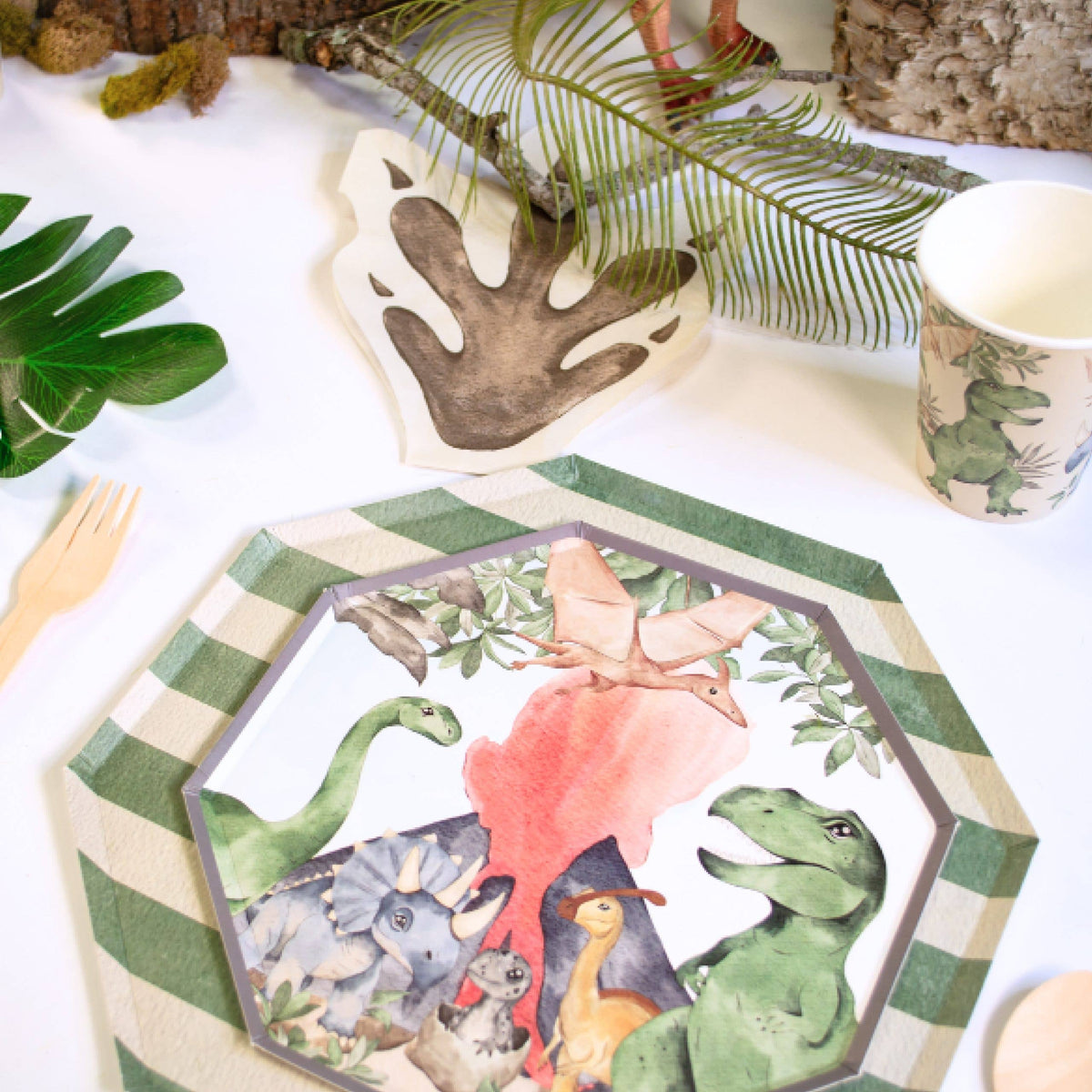 Alt Text: A dinosaur plate styled on a striped plate with jungle greenery and a footprint napkin