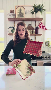 Woman showing Holly Square Scalloped Christmas Plates with coordinating holiday tableware