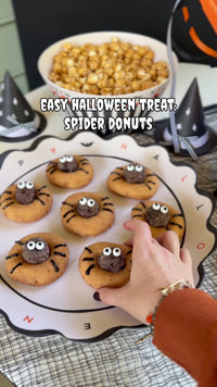 Making Halloween bat donuts with chocolate frosting and candy eyes, served on a scalloped Happy Halloween platter
