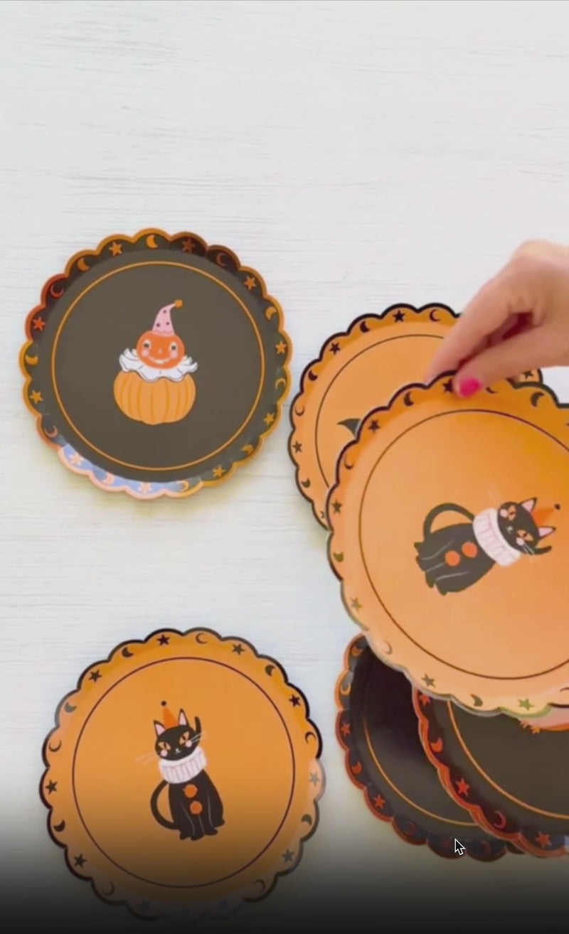 Video of the Halloween Party Animals paper plates — black and charcoal plates with orange scalloped foil star and moon edges, showing the four party-hat characters (pumpkin, black cat, bat, and owl) styled on a Halloween table.