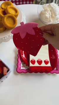 A vertical product showcase video highlighting a whimsical strawberry-themed party collection. The video features close-ups of illustrated paper plates and napkins before panning out to reveal a complete strawberry shortcake dessert table with fresh fruit, shortcakes, and a matching berry centerpiece.