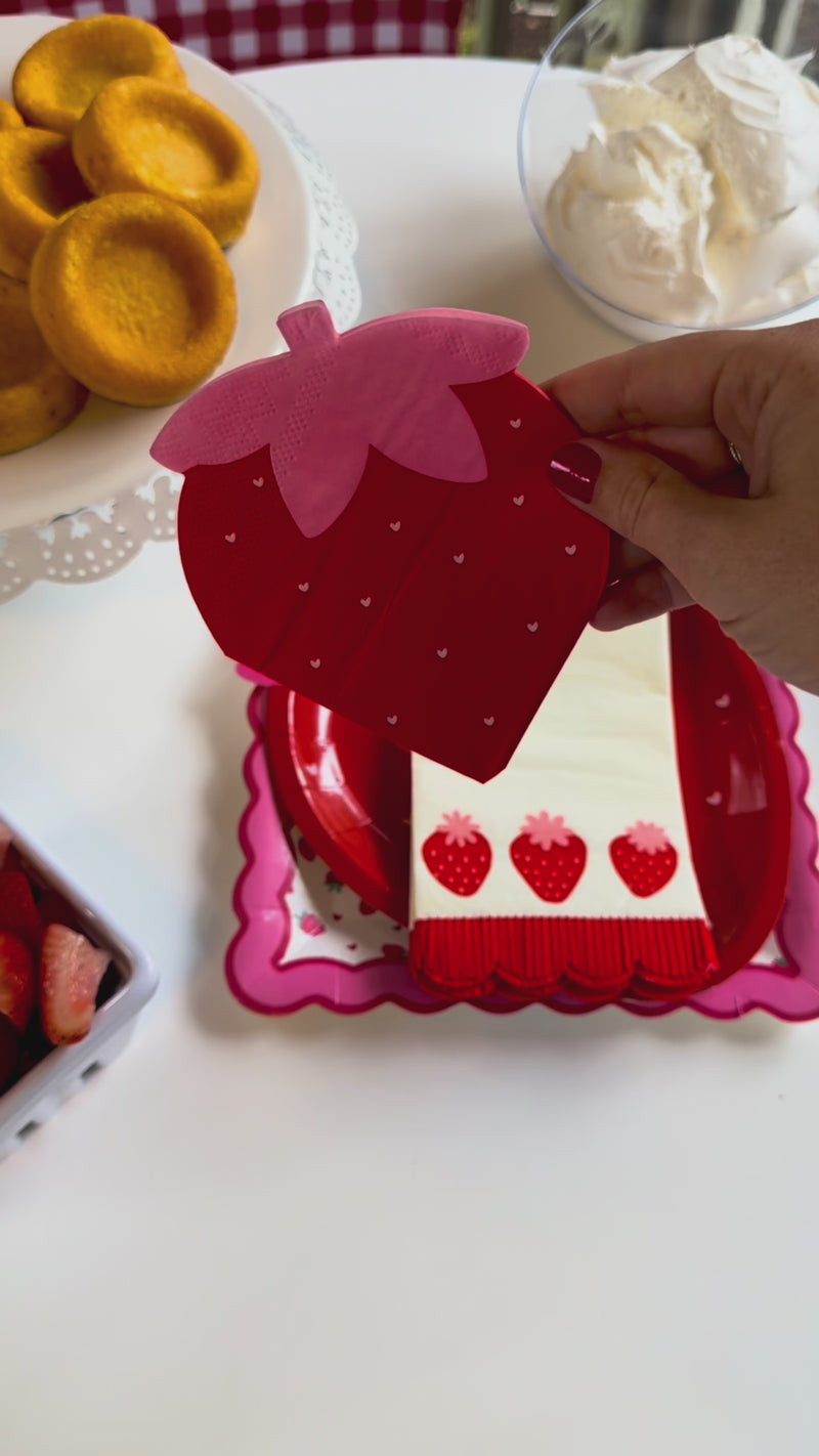 A vertical product showcase video highlighting a whimsical strawberry-themed party collection. The video features close-ups of illustrated paper plates and napkins before panning out to reveal a complete strawberry shortcake dessert table with fresh fruit, shortcakes, and a matching berry centerpiece.