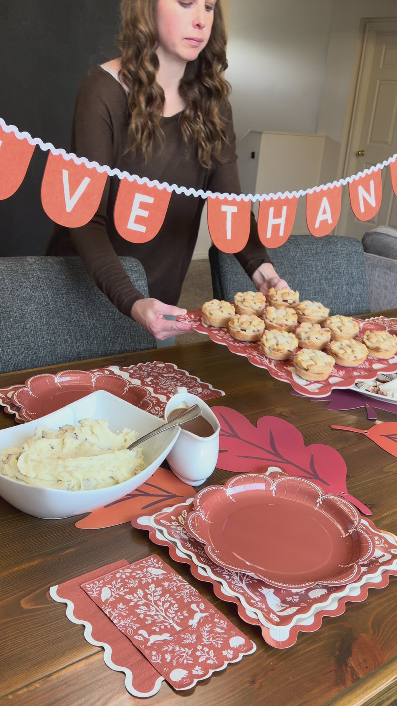 Setting up a Thanksgiving table with the Woodland Thanksgiving party kit, layering rust, ric rac, and woodland plates with napkins and the bamboo tray