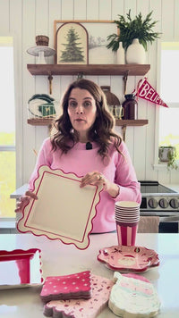 Woman displaying Red Scalloped Christmas Paper Plates with coordinating tableware
