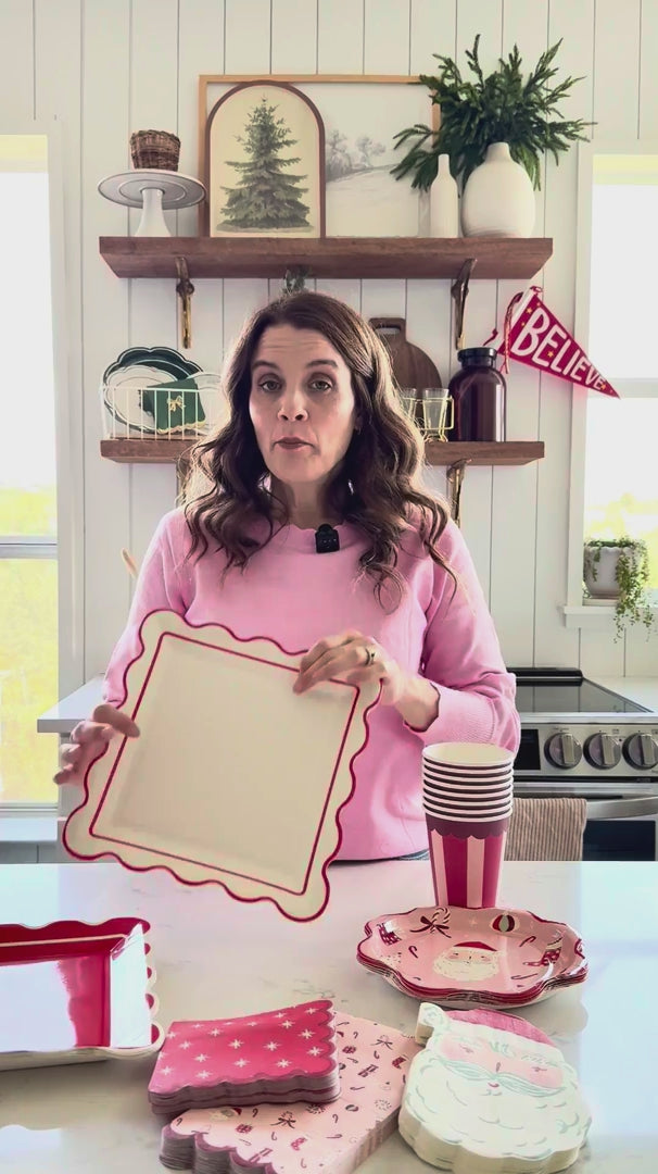 Woman displaying Red Scalloped Christmas Paper Plates with coordinating tableware