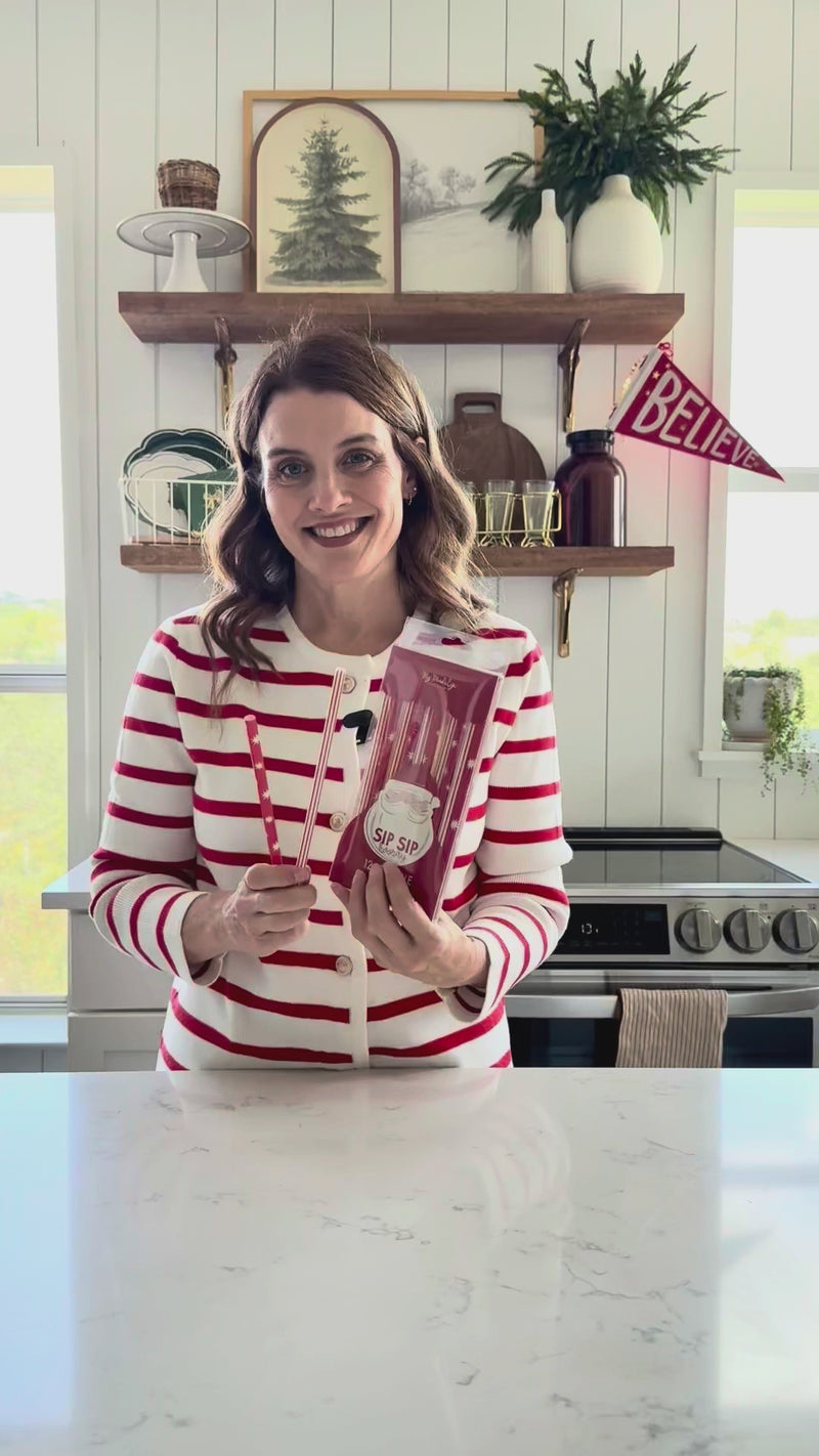 Video demonstration showing a person holding and describing the Believe Reusable Plastic Straws, highlighting the 12-count set, stripe/star patterns, and dishwasher-safe feature for Christmas and holiday party supplies.