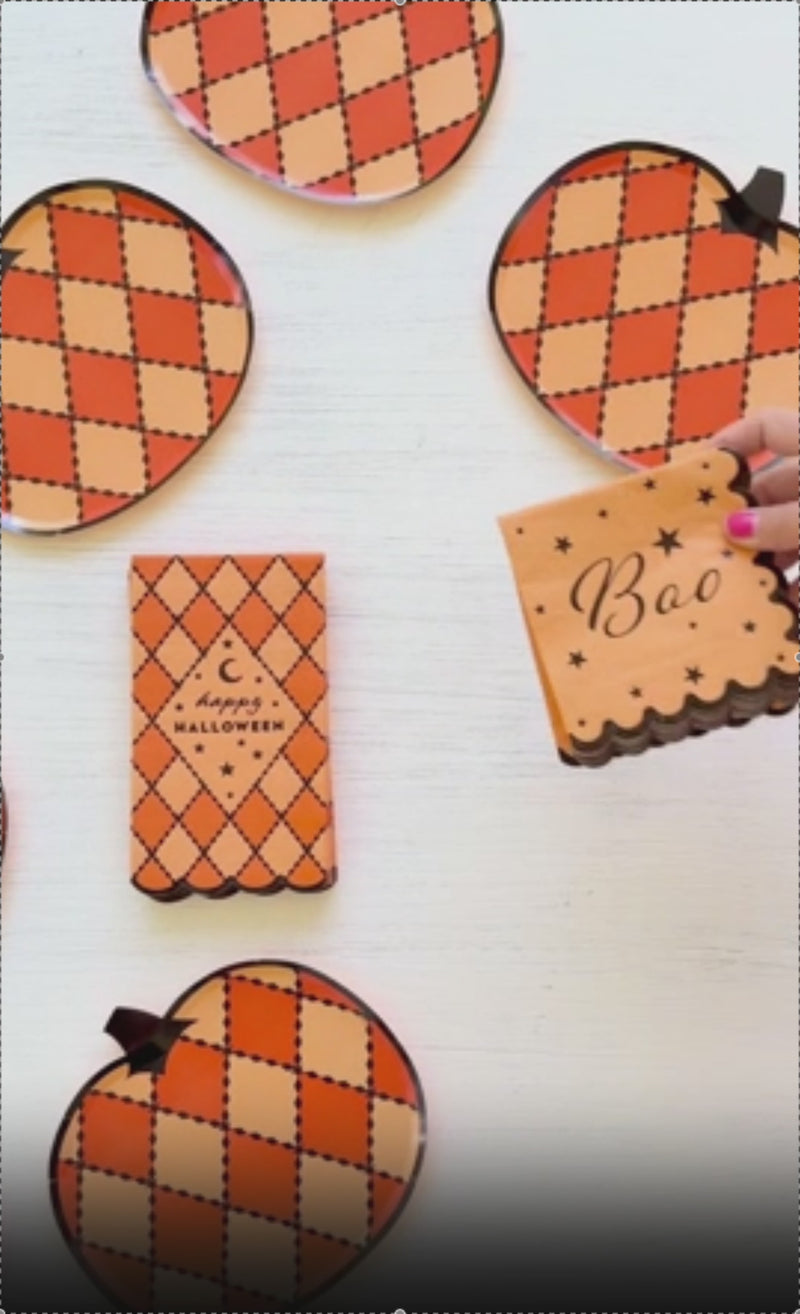 Video of the Harlequin Halloween pumpkin-shaped paper plates — die-cut pumpkins in orange and marigold argyle with black diamond lines and a black stem, shown styled on a fall Halloween table.