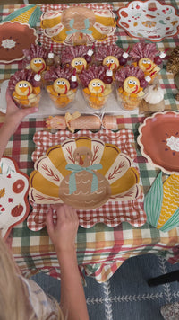 Thanksgiving table set with turkey plates, fall print scalloped plates, pie plates, Happy Thanksgiving and corn napkins, gingham placemats and turkey crackers