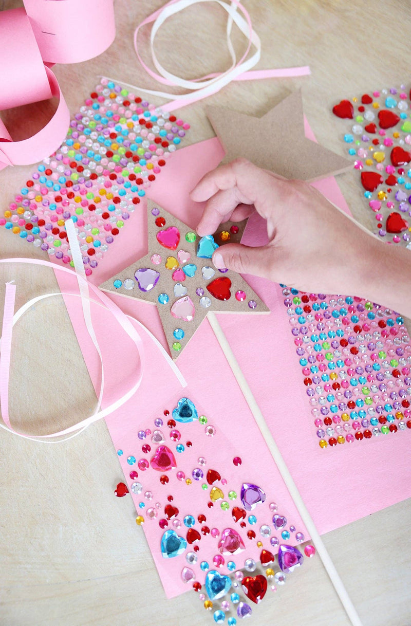 A child's hand placing heart-shaped gems on a Customizable Fairy Wand as part of a Birthday Party Craft Station.