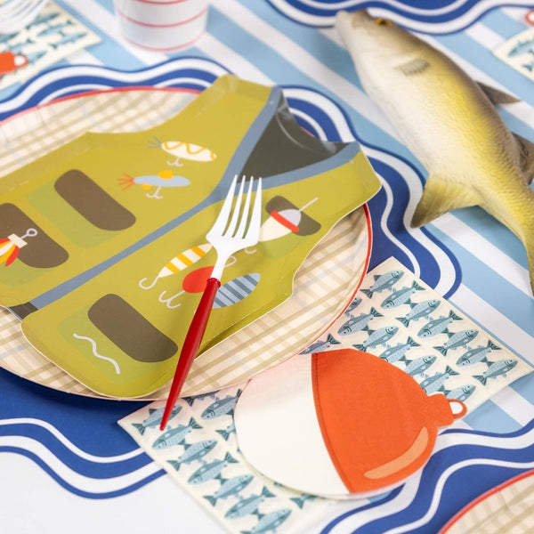 Fishing vest shaped plate with a fork, fish print napkin, and bobber napkin on a striped table cover.