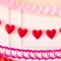 Puffy heart felt banner hanging on wall with pink and red party décor