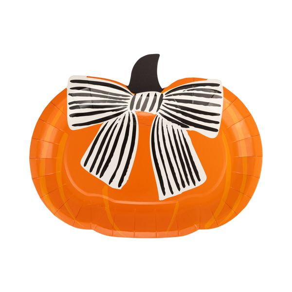 Die-cut orange pumpkin shaped Halloween paper plate with a large black-and-cream striped bow and dark stem, front view on white background.