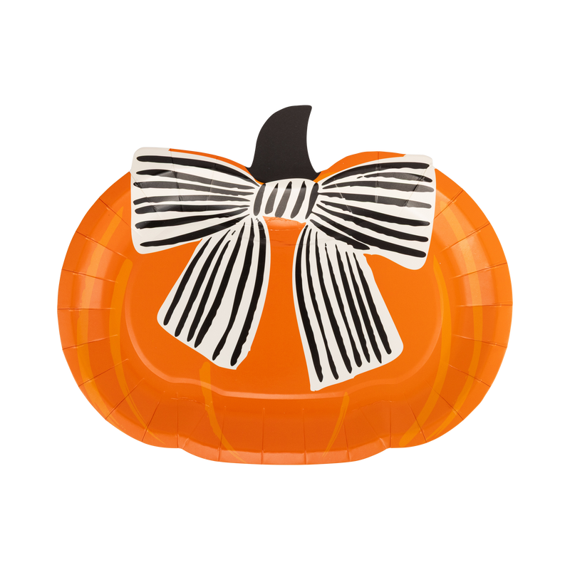 Die-cut orange pumpkin shaped Halloween paper plate with a large black-and-cream striped bow and dark stem, front view on white background.