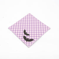 Single purple checkered bat paper cocktail napkin angled on a white background