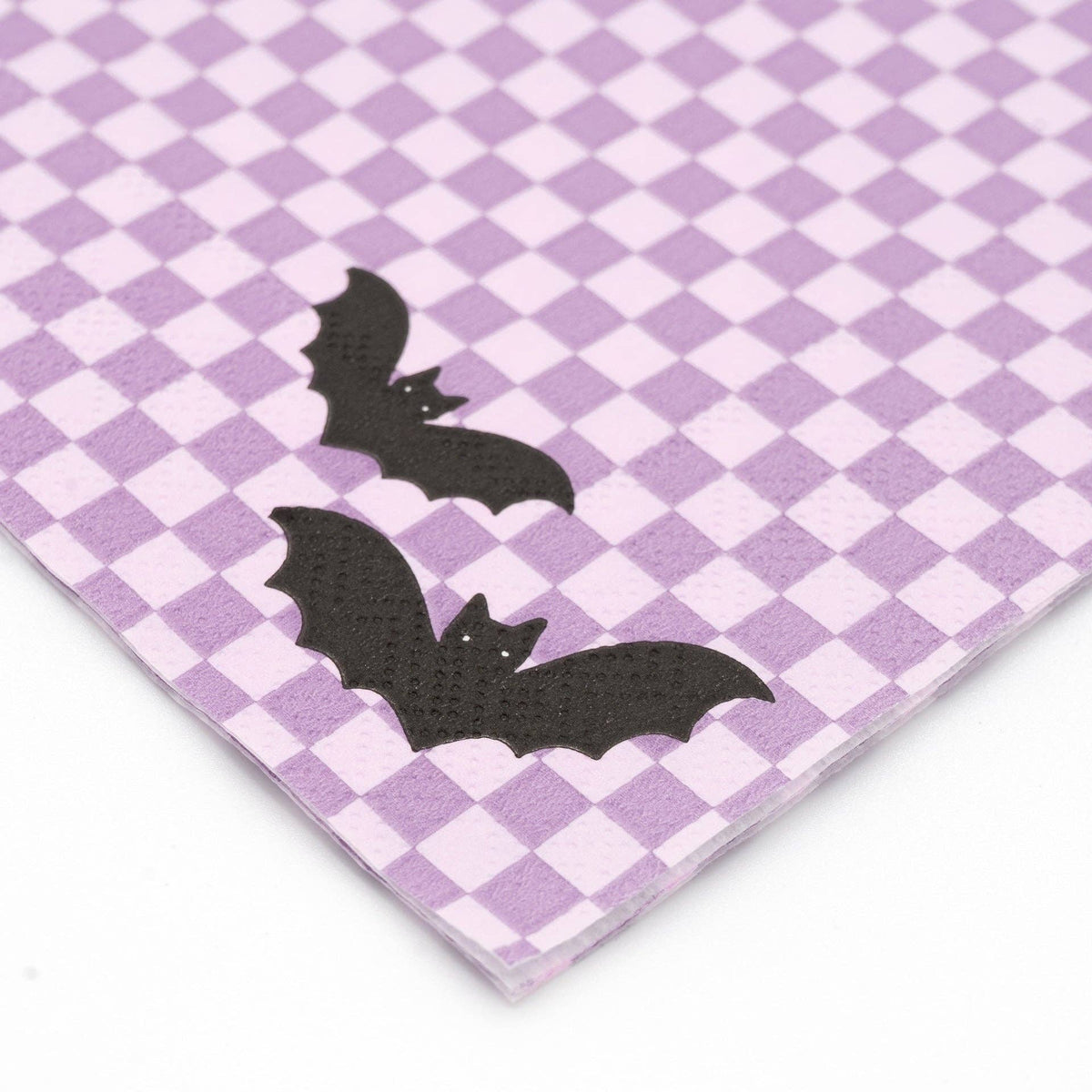 Close-up detail of lavender checkerboard paper napkin showing embossed texture and black bat print