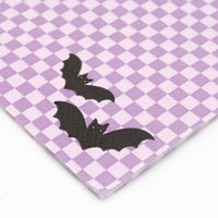 Close-up detail of lavender checkerboard paper napkin showing embossed texture and black bat print