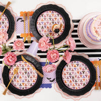Purple checkered bat napkins styled with black scalloped charger plates and gold flatware on a striped runner