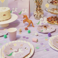 Unicorn themed dessert table with purple cups and matching favor bags