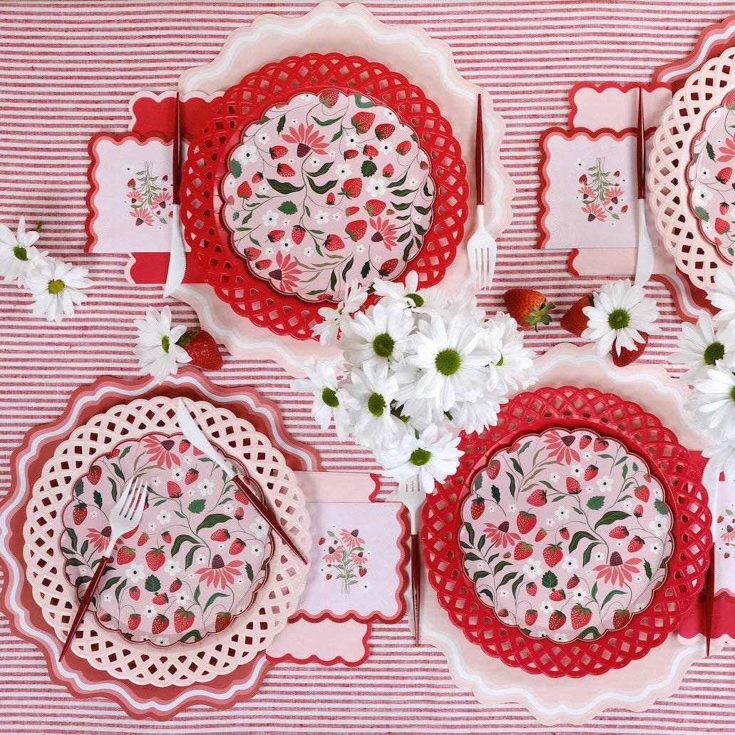red basketweave plates styled in table setting with striped linens and strawberries.