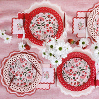 red basketweave plates styled in table setting with striped linens and strawberries.