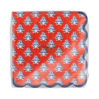 Red block-print floral paper cocktail napkins in packaging showing full indigo blue floral pattern on red base with navy scalloped edge