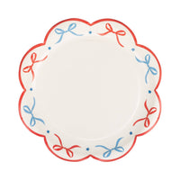 Single red and blue bow scalloped paper plate flat lay on white background showing full bow and star border design with red scalloped edge
