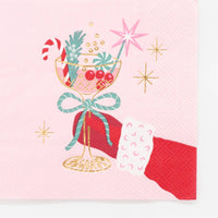 Close-up macro detail of the bottom half of the pink napkin illustration, highlighting the red winter glove, coupe glass stem, and blue ribbon bow.