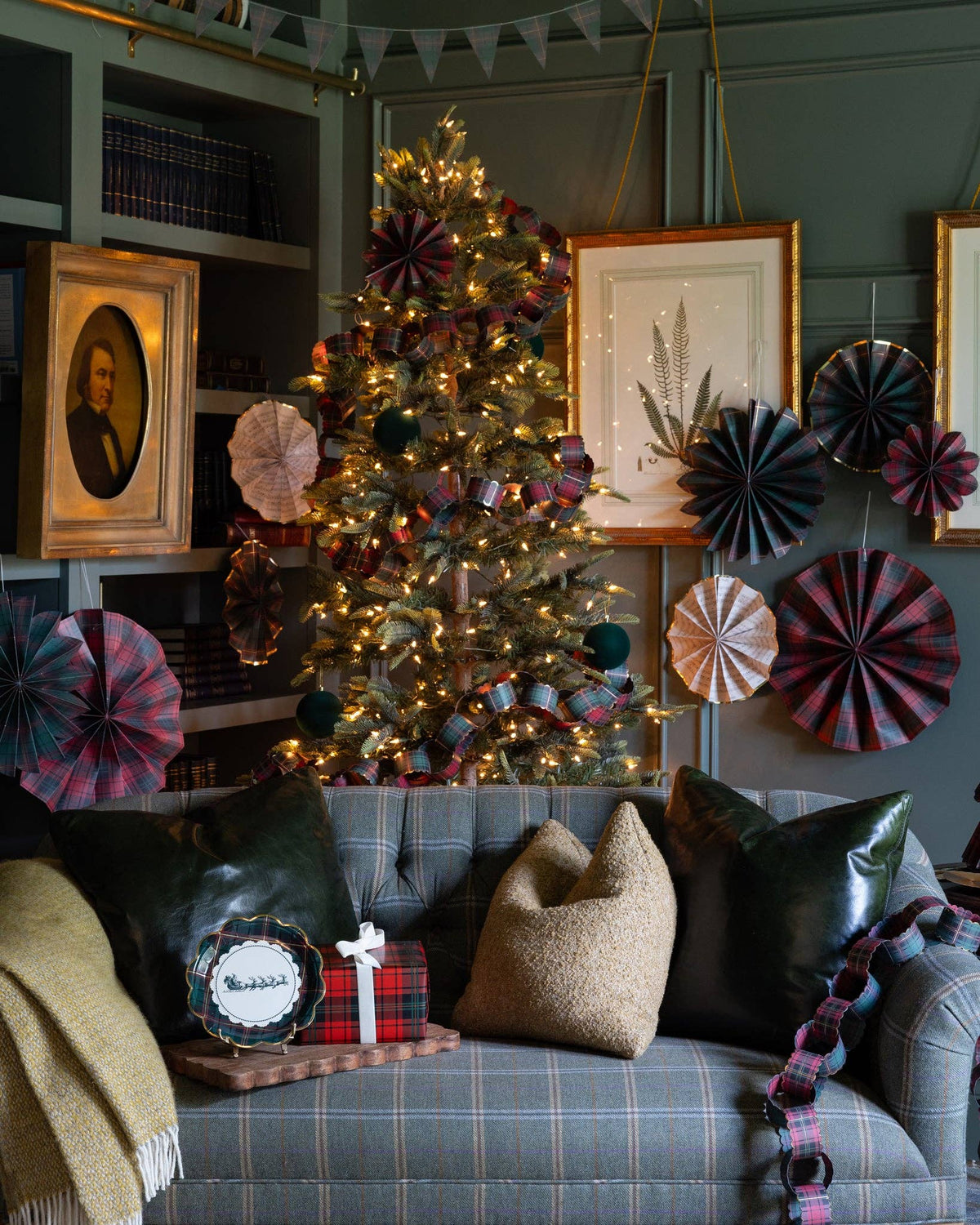 Plaid Christmas paper fans styled in a living room with a tree and sofa