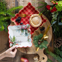 Holiday table setup with red plaid plate under holly plate on rustic wood board