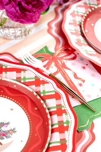 Close-up overhead shot of a red and white fork resting on the pink Christmas present napkin over a green base.