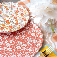 Cream fall floral plate resting on a rust floral plate beside a peony in a ribbed vase