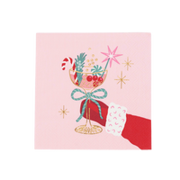 Top-down studio view of a pink square paper cocktail napkin featuring a retro illustration of a red-gloved hand holding a festive coupe glass with a candy cane.