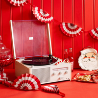 Retro holiday party setup with record player, red and white fan bunting banner, and vintage Santa tableware.