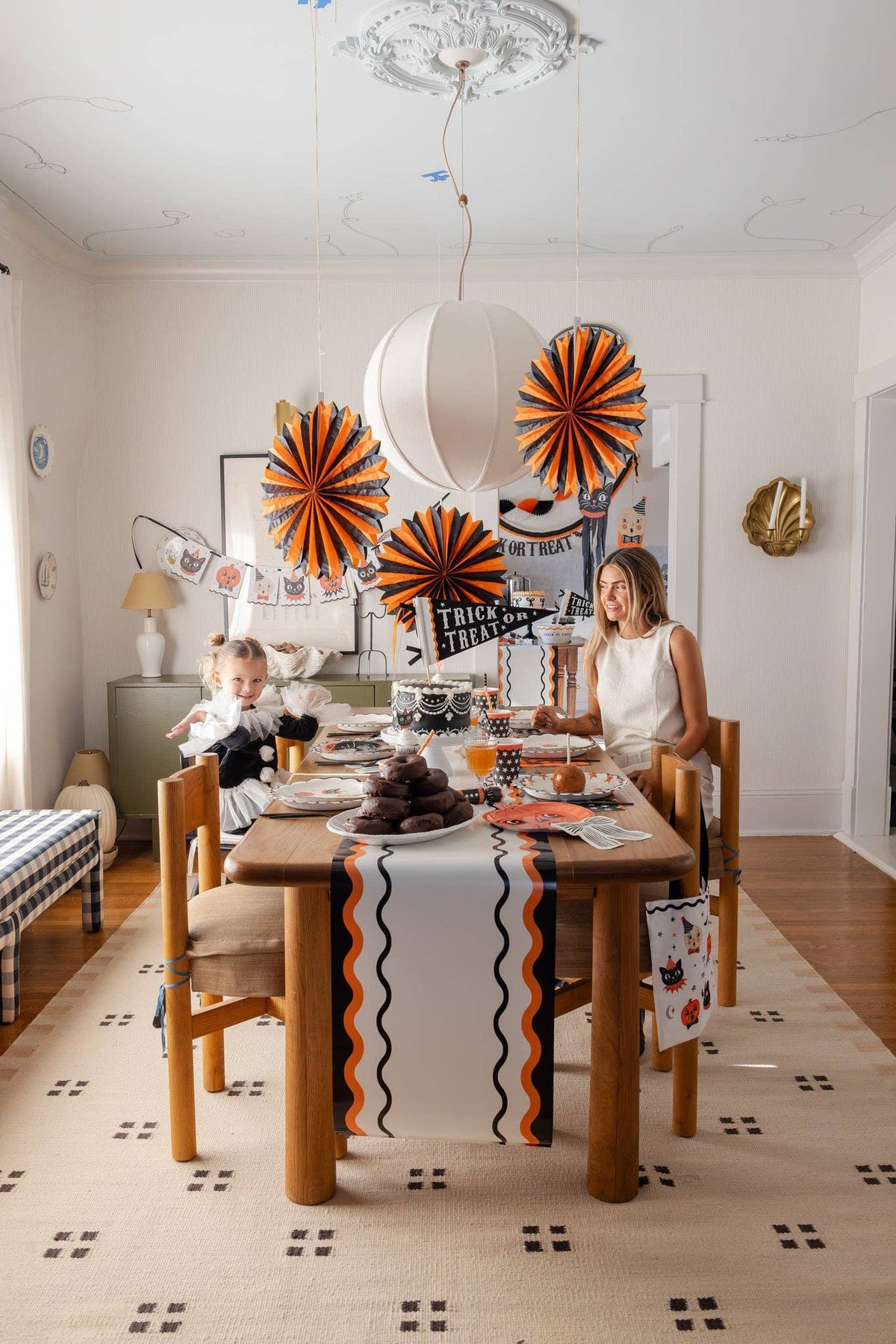 Dining room with Halloween decorations, including paper fans and a table runner.