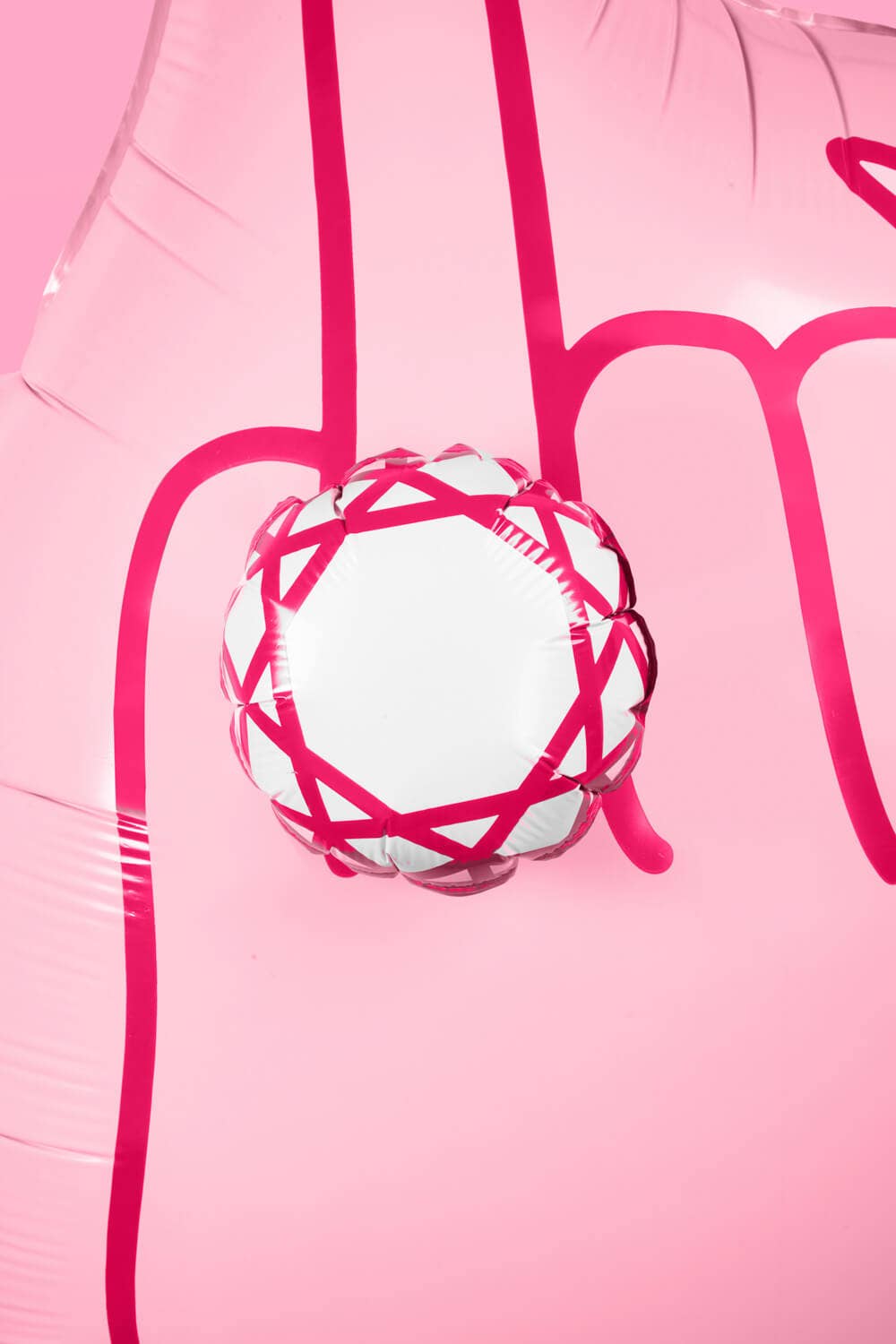 Extreme close-up of 3D diamond ring detail on ring finger balloon showing white and hot pink geometric facets