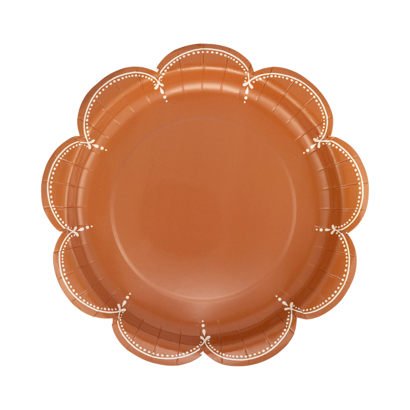Overhead studio view of a round terracotta rust paper plate featuring a white stitched border along a scalloped edge.