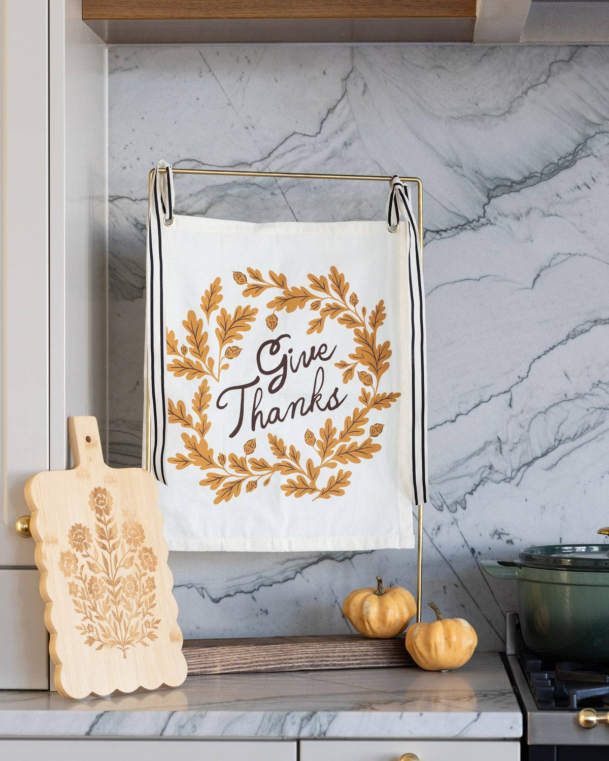 Wide lifestyle shot of the autumn canvas banner anchored against a grey marble kitchen backsplash next to a carved wooden board.