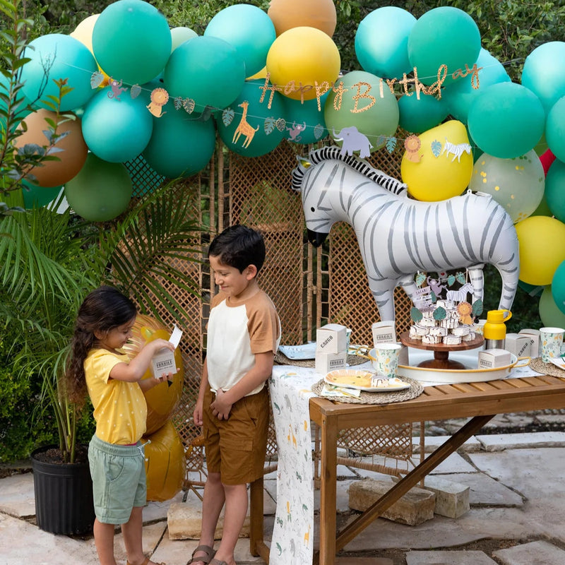 Outdoor safari theme party setup with zebra balloon and ‘happy birthday’ banner.