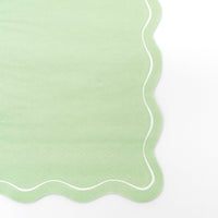 Close-up of the sage green paper guest towel showing the flowing scalloped edge and white outline detail.