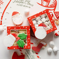 Overhead close-up of two assembled red window Christmas treat boxes with cookies and candy