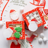 Overhead trio of red window Christmas cookie boxes with twine and Santa tag
