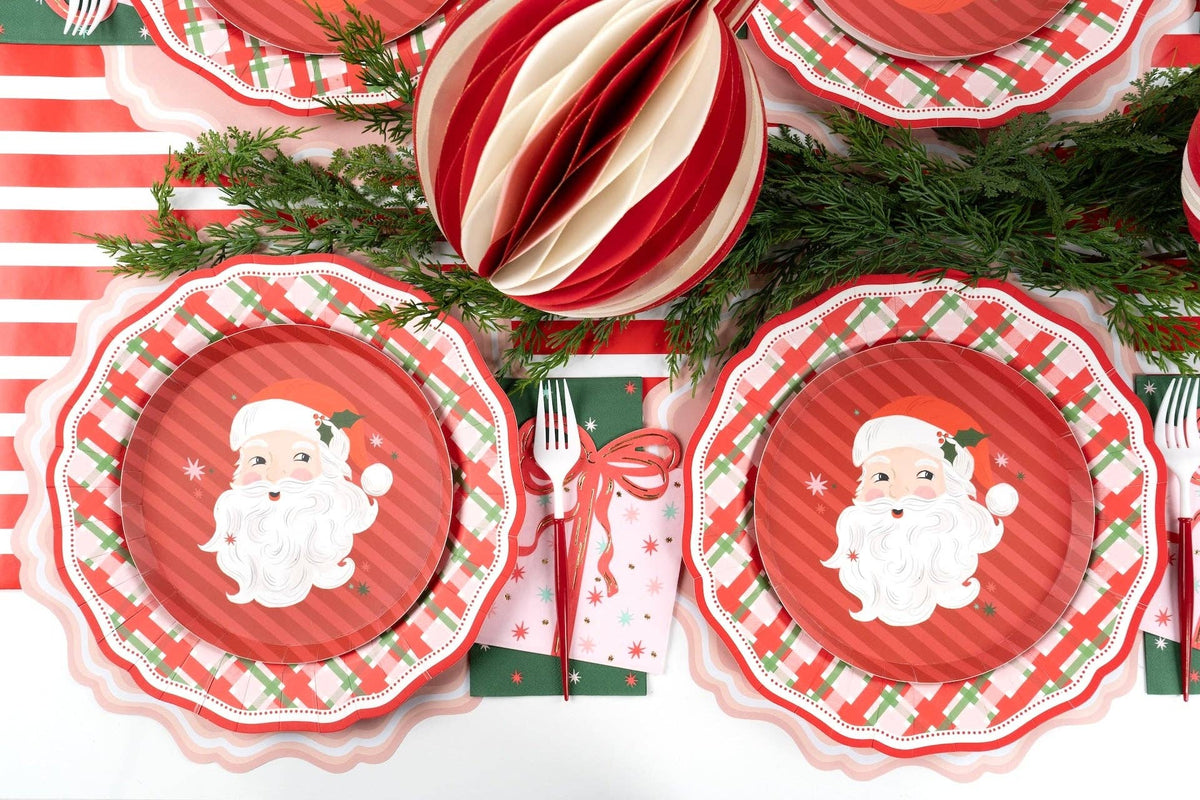 Striped ornaments beside Santa dessert plates with evergreen and gold cutlery.