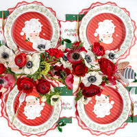 Overhead of four Santa dessert plate settings with red anemones and a striped runner.