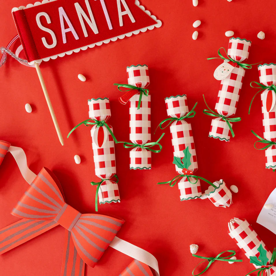 Red tabletop with Santa felt pennant, crackers, and game cards—cheery holiday decorations.