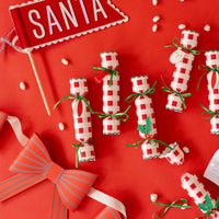 Red tabletop with Santa felt pennant, crackers, and game cards—cheery holiday decorations.